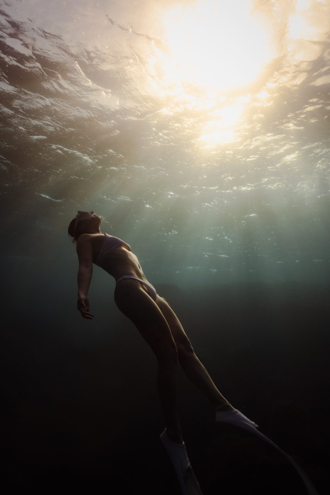 A freediver rising toward sunlight in open water